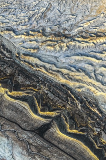 Aerial photograph showcasing the intricate golden sandstone formations of the Utah desert. The texture and patterns reveal the natural beauty and geological history