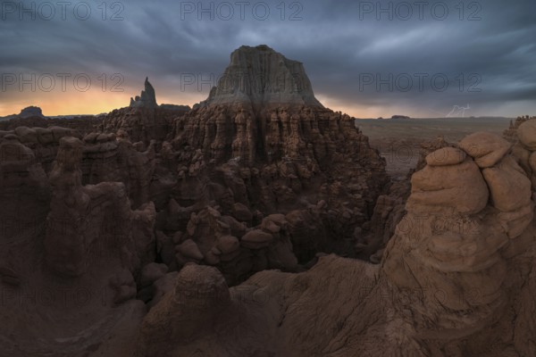 Captivating view of dramatic sandstone formations in Goblin Valley State Park, Utah, at dusk. The striking contrast between shadows and the illuminated sky creates an awe-inspiring scene