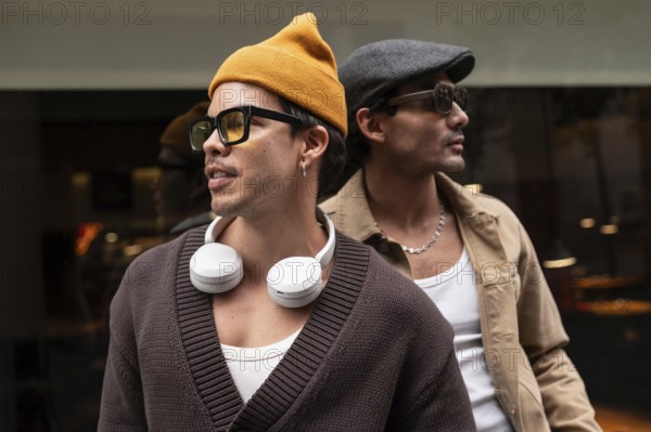 A Colombian gay couple enjoying a relaxed moment together. They wear fashionable clothes, sunglasses, and hats, sitting closely with a sense of camaraderie and warmth