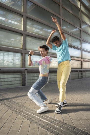 A vibrant gay couple dances joyfully outside, expressing happiness and freedom. Colorful outfits and energetic movements capture a lively, positive spirit in an urban setting