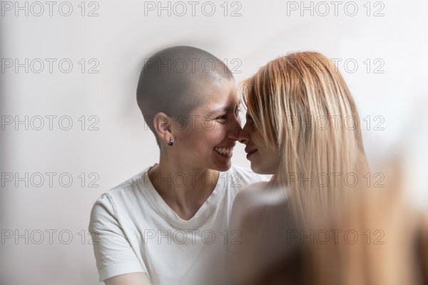 A tender moment captured between a joyful lesbian couple, sharing a loving embrace. Their intimacy and happiness are reflected in their warm smiles and gently touching foreheads