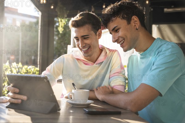 A joyful gay couple shares a moment at a sunny cafe, enjoying coffee and exploring content on a tablet. The scene exudes warmth, love, and companionship