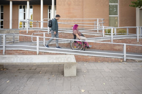 Young couple at college, featuring a woman in a wheelchair due to spina bifida The image highlights accessibility and inclusivity on a campus with ramps