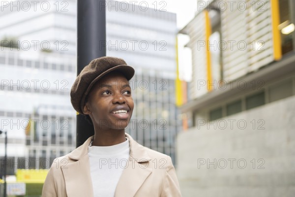 A confident black woman stands outdoors in an urban setting, wearing a stylish outfit The modern cityscape captures a sense of vibrancy and diversity