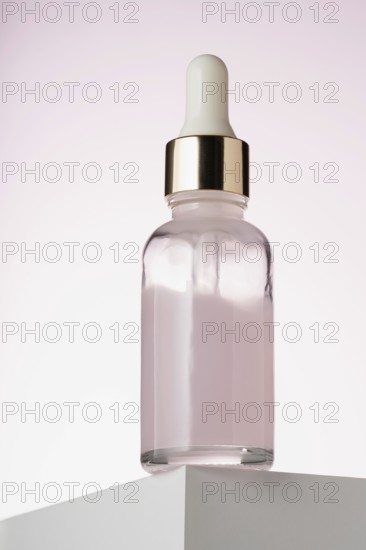 An elegant dropper bottle for cosmetics prominently displayed on a two toned minimalist podium, emphasizing its sleek design and luxury appeal