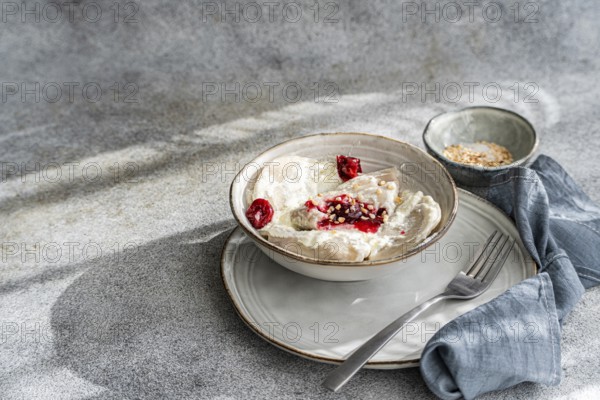 Traditional Ukrainian varenyky filled with cherries, served with rich sour cream and sprinkled with chopped nuts. A delicious blend of sweet and creamy flavors