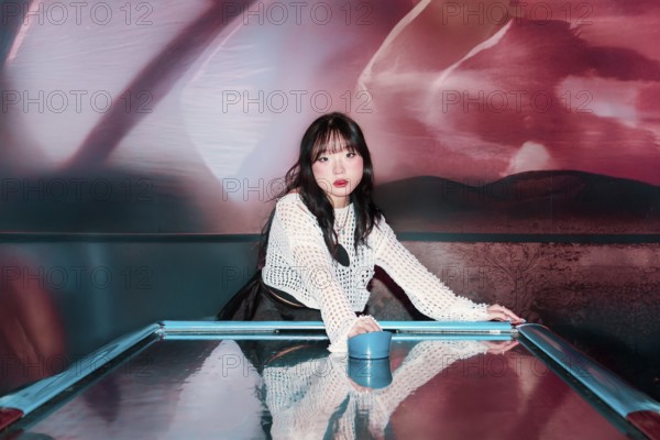 An Asian Gen Z girl enjoys a thrilling moment in an arcade, immersed in vibrant surroundings Her enthusiasm reflects the lively energy of the gaming space