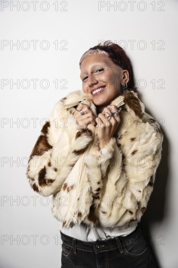 A woman with short hair smiles warmly at camera while wearing a fashionable faux fur jacket