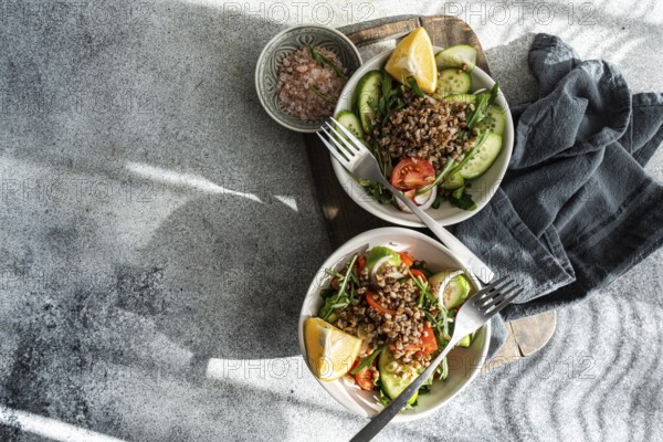 Delicious and healthy lunch with fresh rocket, chopped oregano, cherry tomatoes, cucumber, Himalayan salt, red onion, steamed buckwheat, lemon, and organic olive oil