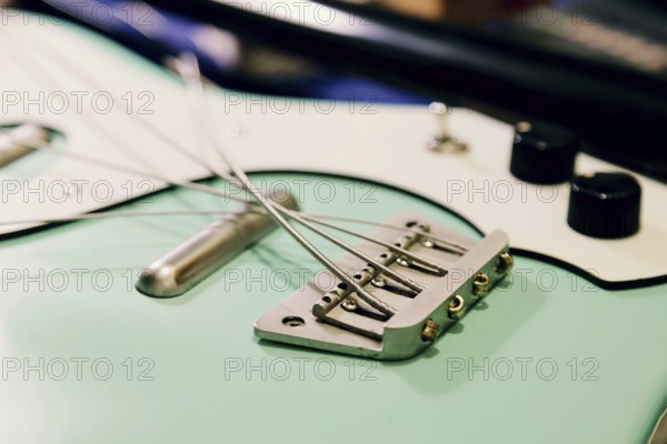 Close-up of a bass guitar bridge and strings in a luthier workshop. The focus is on the intricate details of craftsmanship and the assembly process