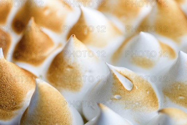 Detailed close up of perfectly toasted meringue peaks, showcasing their golden brown color and soft white texture. Ideal for culinary and dessert themed projects