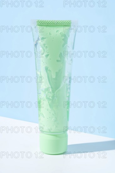 Transparent green tube filled with aloe vera infused cosmetic gel showcased against a light blue background, highlighting its soothing and hydrating properties