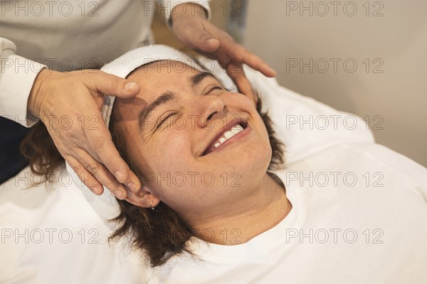 A man enjoys a relaxing facial massage using organic products The atmosphere is serene, promoting wellness and self-care The man wears a headband while lying on a massage table