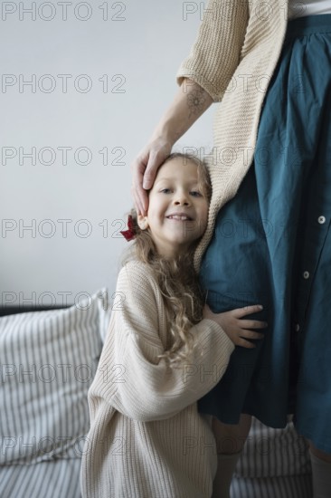 A young girl smiles while hugging her mother, showcasing a sense of warmth and security The scene conveys love and family bonding in a cozy home environment