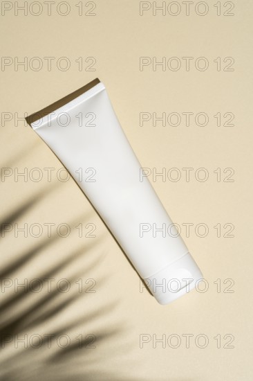 Top view of a minimalist designed cosmetic tube stands against a beige background, casting soft shadows that evoke a serene, sophisticated vibe