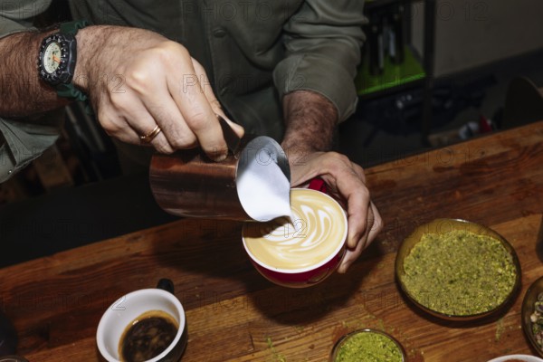 A barista delicately pours steamed milk into a latte, creating intricate latte art. The scene captures the essence of specialty coffee brewing and skilled craftsmanship
