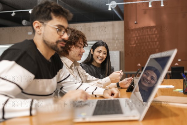 A group of diverse coworkers collaborating in a modern office setting, using laptops and tablets They are engaged in a productive and friendly discussion, emphasizing teamwork