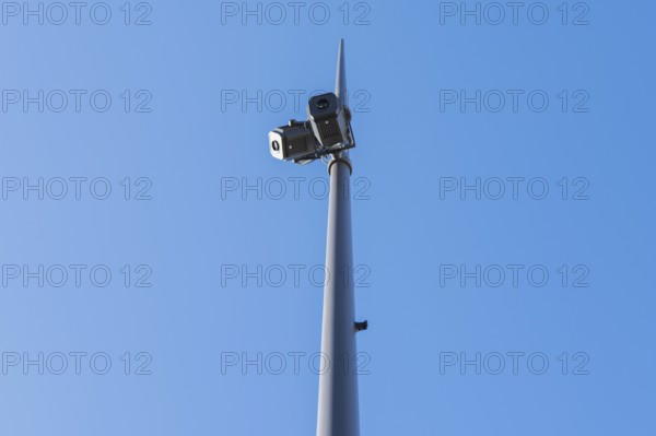 Low-angle view of surveillance cameras mounted on a tall pole, set against a clear blue sky. The image showcases security and technology in outdoor settings