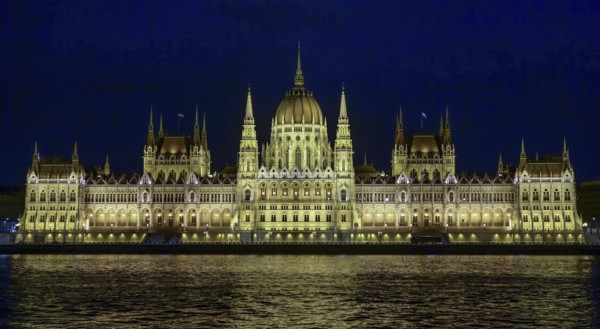 The Hungarian Parliament Building, illuminated at night, reflects its grandeur on the waters of the Danube River