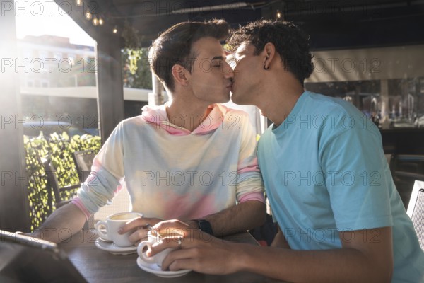 A loving gay couple shares a tender kiss while enjoying coffee at an outdoor cafe. Their connection is highlighted by the warm sunlight and vibrant surroundings