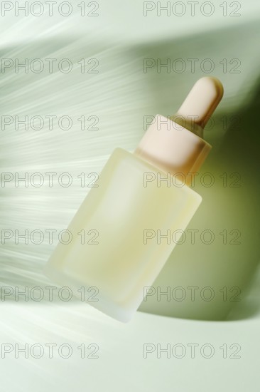 A frosted glass serum dropper bottle hovers against a blurred green background, depicting motion and organic freshness, perfect for skincare branding