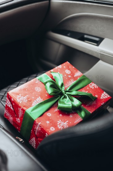 A beautifully wrapped red gift with a green ribbon rests on a car seat, capturing the anticipation of giving during the holiday season Perfect for festive themes