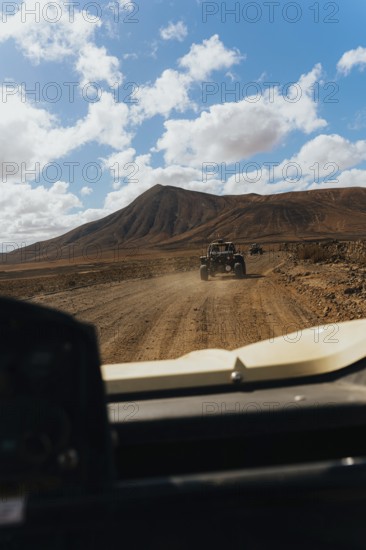 Lanzarote's rugged terrain from a buggy. Vast volcanic landscapes, scattered clouds and a scenic drive capture the essence of adventure and natural beauty
