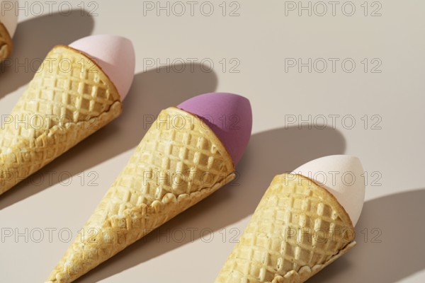 Innovative arrangement of colorful cosmetic sponges nestled in waffle cones, set against a soft, neutral background The image combines beauty and playful creativity