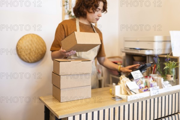 A small business owner multitasking in a shop shop, handling cardboard packages while preparing for delivery The warm ambiance highlights the entrepreneurial spirit