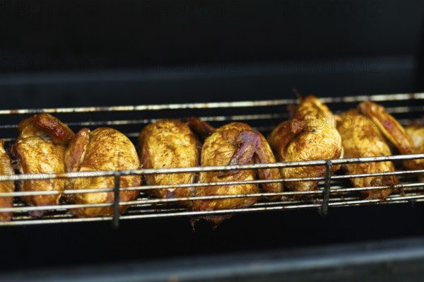 Juicy grilled chickens cooking on a metal rack, highlighting the vibrant street food scene at an outdoor fair