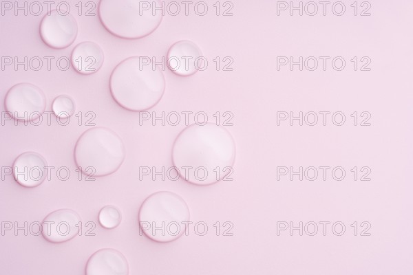 This image displays a pastel pink background with clear droplets, creating a serene and calming visual texture Ideal for beauty, skincare, or relaxation-themed projects