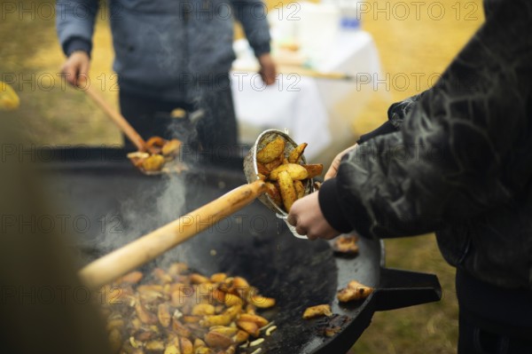 Cropped unrecognizable staff cooking potatoes at a bustling street food fair, enhancing the aroma with smoky flavors, creating an enticing atmosphere for fair-goers who enjoy outdoor culinary experiences
