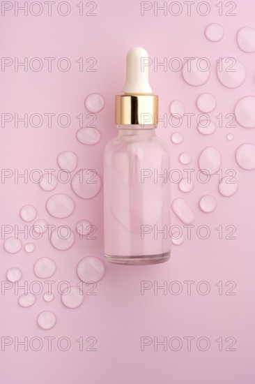 A clear glass dropper bottle on a pink background, surrounded by scattered water drops The scene evokes freshness, beauty, and skincare elegance