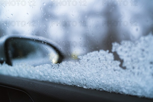 Close-up of a frosted car window with a blurred side mirror visible. The ice crystals and droplets create a wintry atmosphere in the Swedish Lapland
