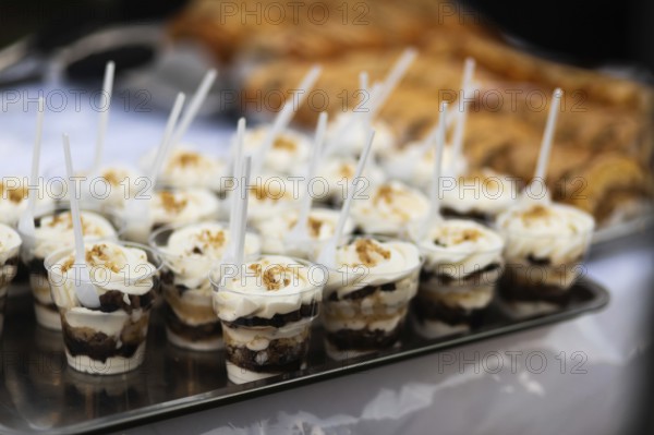 A tray of delicious layered dessert cups, each topped with whipped cream and crunch, beautifully presented at a street food fair