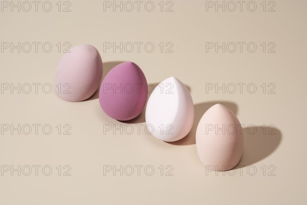A row of pastel cosmetic sponges in various soft tones on a neutral backdrop, showcasing their smooth texture and versatility for flawless makeup application