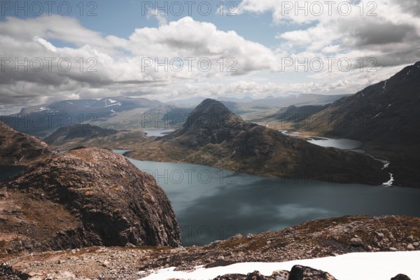 A stunning panoramic view of rugged mountain peaks and pristine lakes in Norway The dramatic terrain and expansive sky create a breathtaking Nordic wilderness scene
