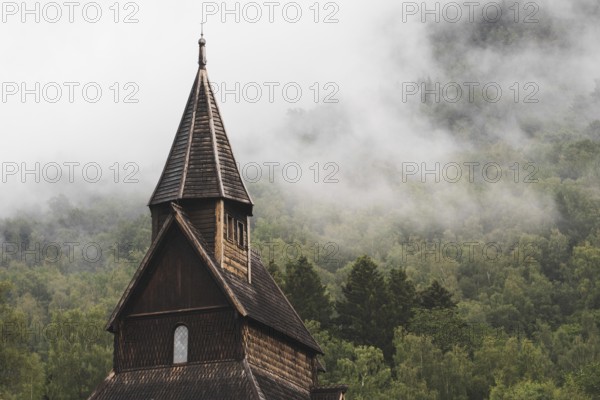 Discover the serene beauty of an ancient Norwegian stave church set against a mist-covered forest backdrop, epitomizing the country's rich history and natural charm