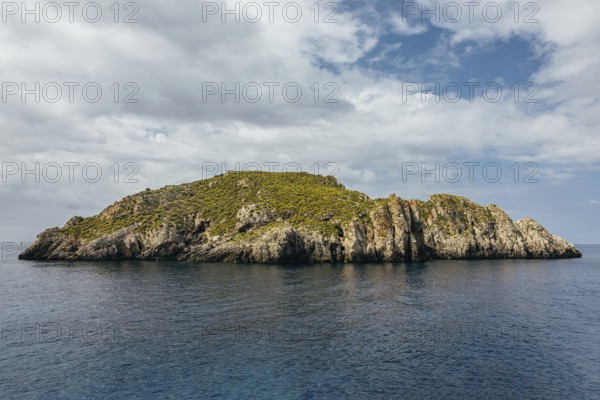 Scenic view of rough mounts with green grass in small island under cloudy sky in daylight