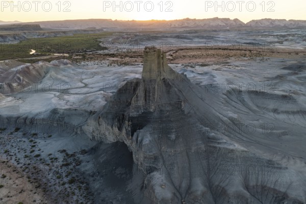 A sweeping aerial view captures the vast, eroded terrain of Utah's desert at sunset, highlighting the intricate geological formations and soft fading light