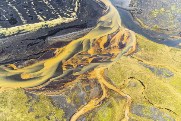 Captivating aerial photograph showcasing the intricate, golden-hued rivers weaving through the rugged landscapes of Iceland, highlighting the unique beauty of its remote areas