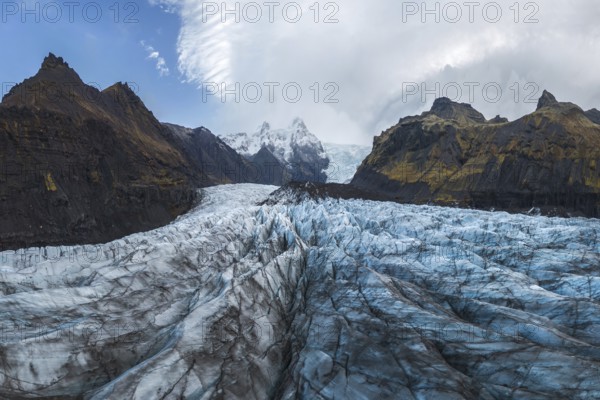 This breathtaking image captures the expansive Vatnajökull Glacier in Vatnajökull National Park, Iceland, surrounded by rugged mountains under a dramatic cloudy sky