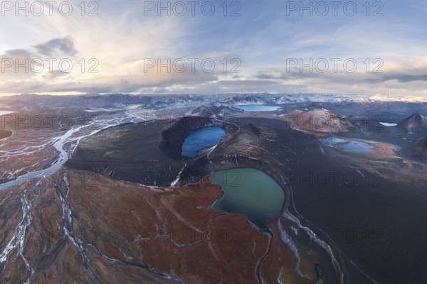 Captivating aerial view of Iceland's Highlands showcasing volcanic craters, vivid blue lakes, and rugged terrain under a dramatic sky, highlighting geological diversity