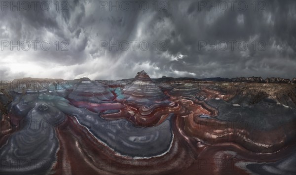 A mesmerizing landscape of colorful, striped geological formations under a dramatic, cloudy sky. The layered hues create an abstract pattern, evoking a sense of awe and wonder