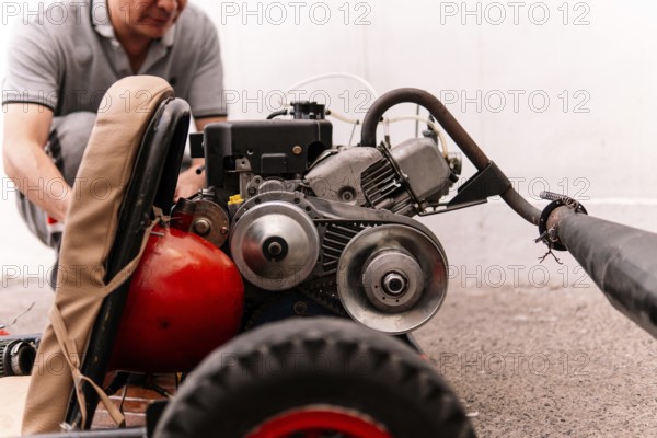 Cropped unrecognizable man is focused on repairing a red engine, showcasing mechanical skills and precision