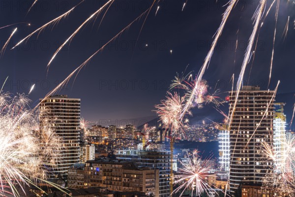 Captivating night view of Tbilisi's downtown skyline illuminated by vibrant fireworks. The urban landscape blends with bursts of color, creating a lively festive atmosphere