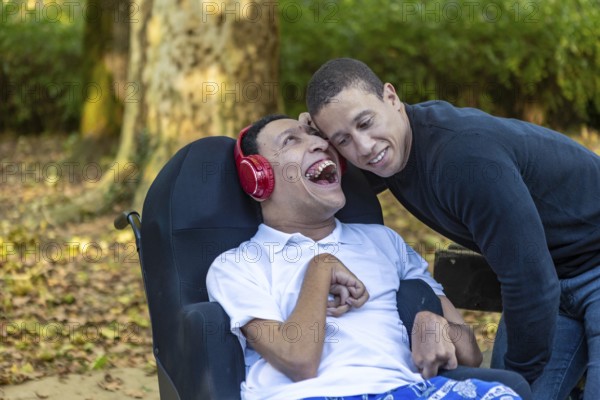 Heartwarming image of Spanish Cameroonian siblings outdoors, one in a wheelchair with cerebral palsy. Their mixed-race heritage adds a rich layer to their joyful bond
