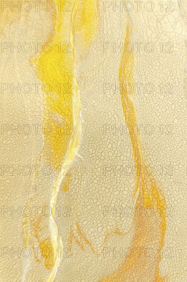 A detailed view of a cracked golden mud surface with flowing yellow lines and intricate patterns, ideal for artistic and textural backgrounds