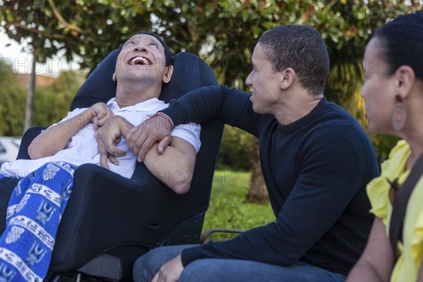 Spanish Cameroonian siblings enjoy time together outdoors. One sibling, with cerebral palsy, smiles warmly. A Mixed-race family showcasing love and connection