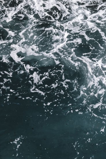 Moving seawater with white foam and dynamic texture. Waves and bubbles create a natural and relaxing pattern